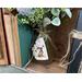 A mason jar flower arrangement sits next to old books. The jar is decorated with a natural birch bark tag. The tag has a bunny drawn on it.